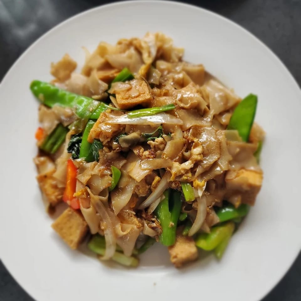 Close-up of Thai Drunken Noodles (Pad Kee Mao) with wide rice noodles, tofu, and green vegetables.