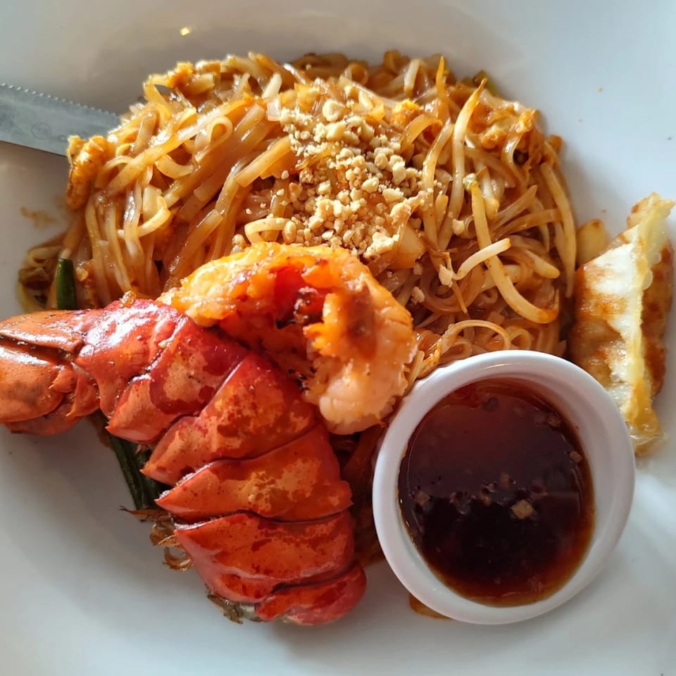 Lobster Pad Thai with peanuts, bean sprouts, and a side of dipping sauce and fried dumplings.